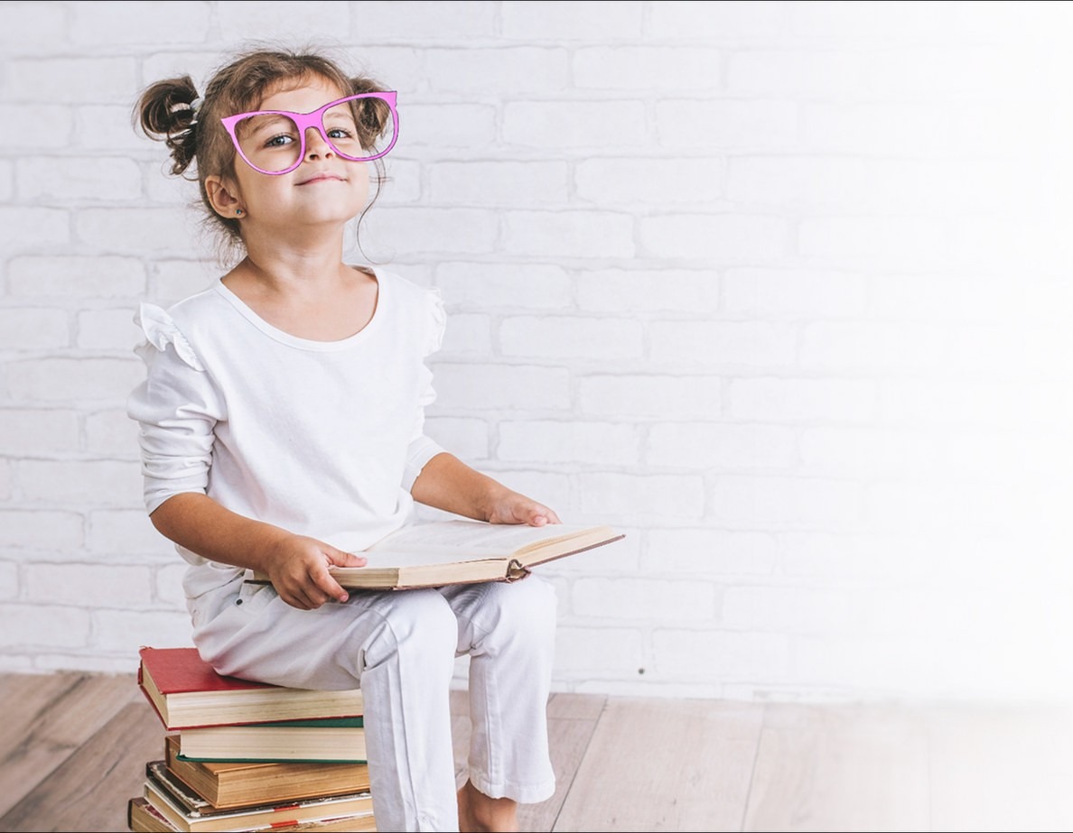 A child reading, sitting on a stack of books